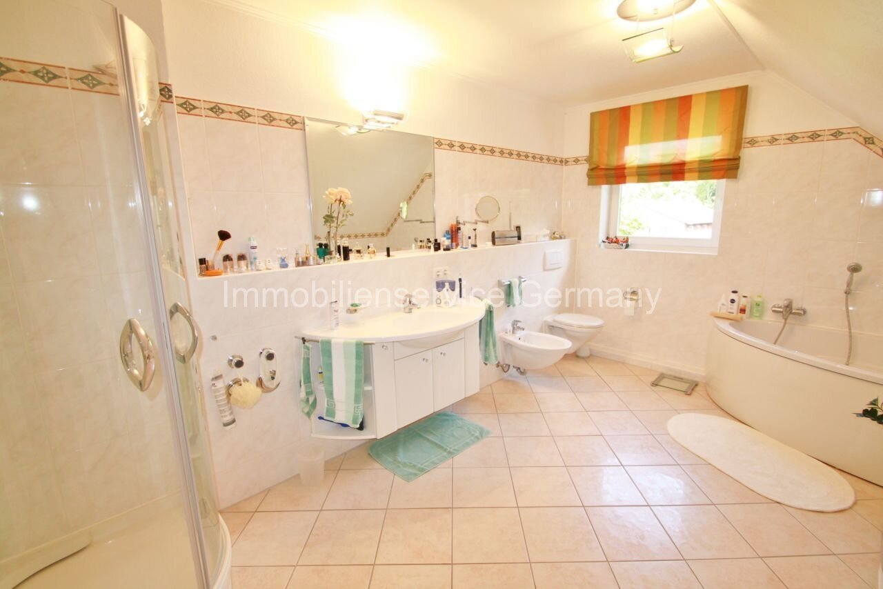 Oasis de bienestar con comodidad: amplio baño con bañera y ducha, diseño sin umbrales y práctico mueble bajo lavabo.